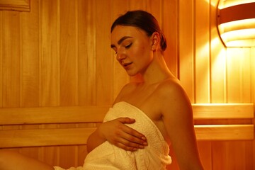 Beautiful woman wrapped in towel at sauna