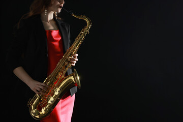 Obraz premium Professional musician playing saxophone on black background, closeup. Space for text