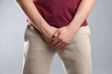 STD (sexually transmitted diseases). Man suffering from symptoms on grey background, closeup