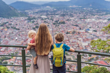 Mom and her two sons, a baby and a teenager tourists in front of the panoramic view of Orizaba from Cerro del Borrego, Mexico. Travel, scenic landscape, and adventure concept