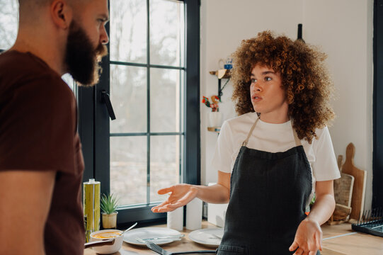 Young couple having disagreement while preparing meal in kitchen