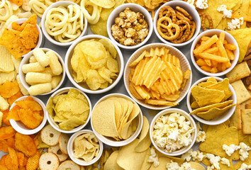 Colorful mix of salty snacks for beer varieties: chips and pretzels, onion rings and crackers. Non-healthy junk food background	
