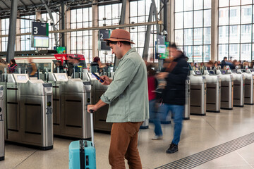 latin Tourist using smartphone and waiting at station gate with luggage