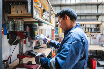 Latin worker using drill press in workshop