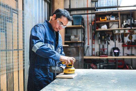 Latin carpenter sanding wood with orbital sander in workshop