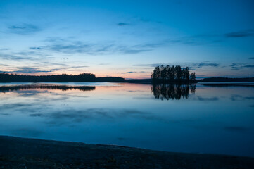 Late evening scenery of a calm lake with a wooden island in the forests of Finland