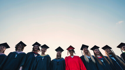 Happy graduates posing for a group photo outdoors in their graduation gowns and mortarboards