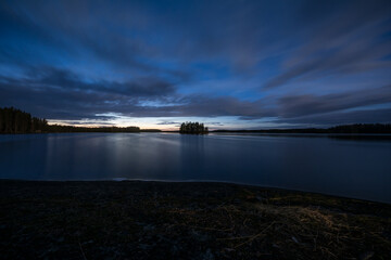 Late evening scenery of a calm lake with a wooden island in the forests of Finland