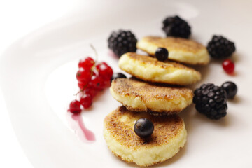 Tasty cheesecakes or pancakes on plate with berries                     