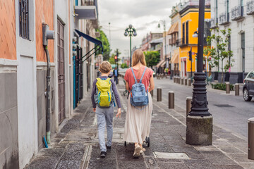 Mother tourist with her toddler and teenage sons walking through the colorful colonial streets of Puebla, Mexico. Travel, cultural exploration, and vibrant architecture concept