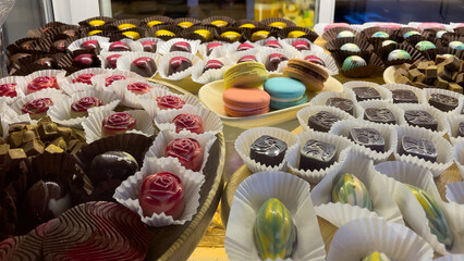 Assorted Handmade Chocolates And Macarons Displayed On A Wooden Tray In A Confectionery Shop, Captured Indoors, Represents Artisanal Desserts, Perfect For Dessert Shops, Cafes, And Food Promotions.