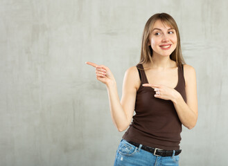 Smiling young woman in casual clothes gesturing in studio
