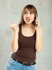 Fototapeta premium Indignant young woman in casual clothes talking on mobile phone in studio