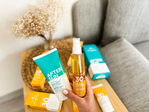 Sun care products displayed on a wooden table with a decorative vase and natural lighting
