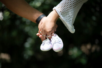 Detail of a couple's hands holding baby shoes