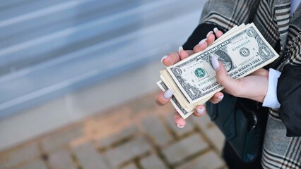 Woman counting a wad of one dollar bills, suggesting financial concepts such as income, budgeting, and savings