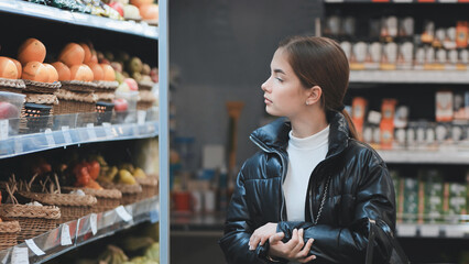 Shopper comparing fresh produce, weighing healthy food choices in grocery store aisle