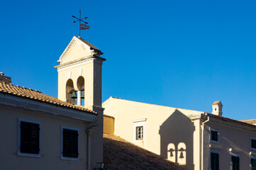 Kerkyra, Corfu. A beautiful building facade with a bell tower against a clear blue sky, capturing the essence of elegance