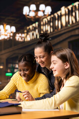 Two preteens scholars and their tutor collaborating on schoolwork at the library, focused on academic success and learning development. Students collect extra information with private lessons.