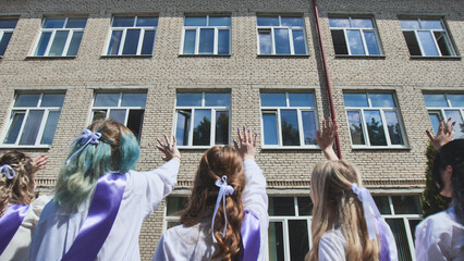 Female graduates waving farewell to their school, marking the end of an era and the start of a fresh journey