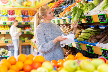 Young woman buying lettuce in the vegetable section of the supermarket