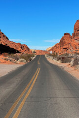 Scenic winding road through red rock formations under a clear blue sky in the desert