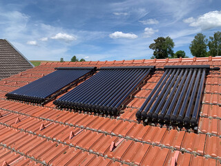 Glass Solar Water Heating Tubes on a Red Tiled Roof of a Residential House