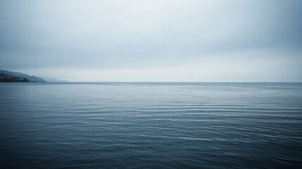 Serene seascape at dusk with calm waters reflecting a cloudy sky and distant hills on the horizon