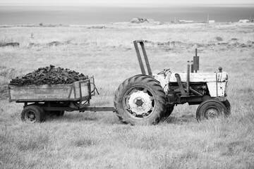 Obraz premium Black and White photo of a full wagon load of Peat/turf pulled by and old tractor in Ireland 