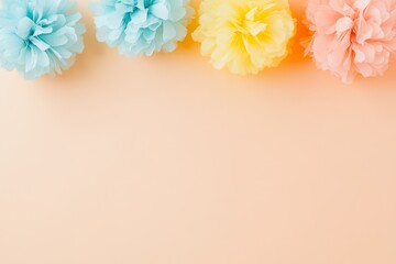 Colorful paper pom poms in pastel shades arranged on a soft peach background, ideal for celebrations
