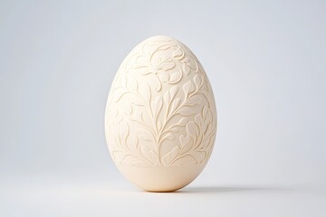 Elegant cream-colored egg with intricate floral carvings against a soft gray background