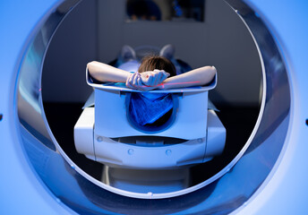 Close up shot of a female patient lying on CT, PET, or MRI scan bed, moving inside the machine....
