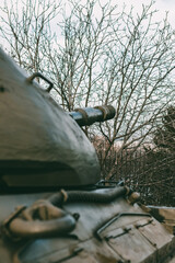 verClose-up of a tank cannon barrel surrounded by leafless trees. Symbol of military power and...
