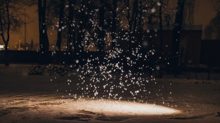 A snowy evening scene featuring delicate snowflakes swirling in the air with a soft glow from underneath, creating a serene and magical atmosphere.