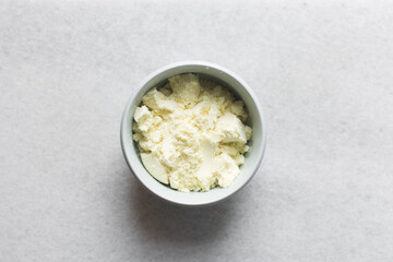 Overhead view of powdered milk in a grey bowl, top view of full fat milk powder in a bowl