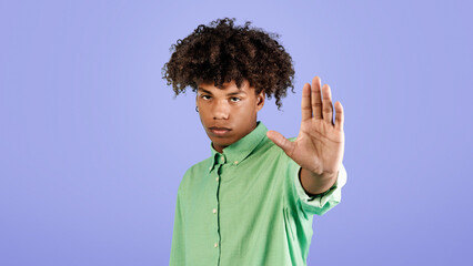 Serious black guy gesturing STOP, saying NO, showing rejection gesture, expressing refusal or...