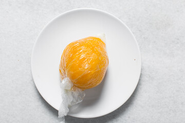 Overhead view of nigerian starch wrapped in cellophane on a white countertop, top view of nigerian...