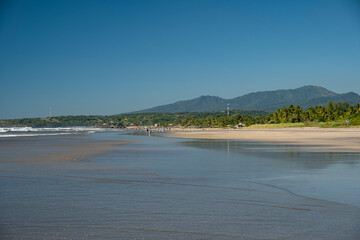 Empty  wide sandy beach during low tide, no locals or tourists around. Sunny day, blue sky. El Cuco, El Salvador.