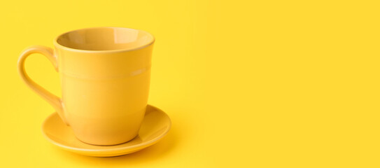 Yellow ceramic cup and saucer on color background