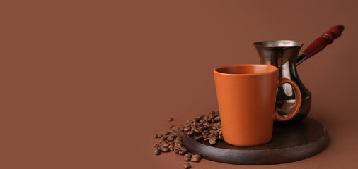 Cup of hot coffee, beans and jezve on brown background with space for text