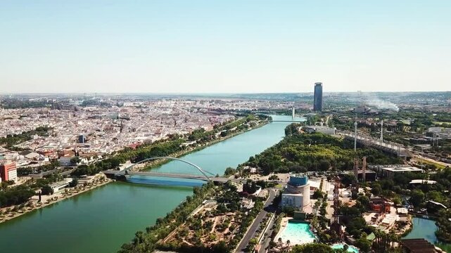 Aerial view of Guadalquivir river crossing Seville with the Alamillo Bridge and Isla Magica theme park, Andalusia, Spain, during a sunny summer day