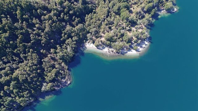 Aerial view of Lago Futalaufquen shore with turquoise waters surrounded by lush forest in Parque Nacional Los Alerces, Chubut Province, Patagonia, Argentina, during a sunny day