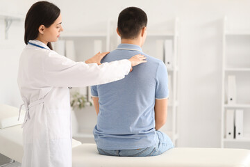 Obraz premium Female doctor checking posture of young man in clinic