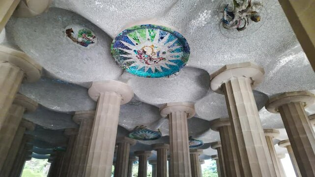 Close up view of the Hypostyle Room in Park G&uuml;ell, featuring intricate columns and mosaic ceiling art, upward interior angle