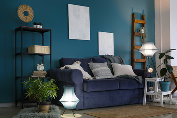 Interior of dark living room with blue sofa and glowing lamp