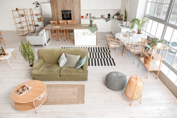 Interior of light open plan kitchen with green sofa and coffee table
