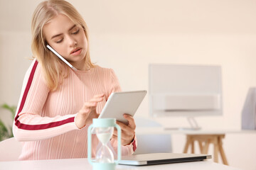Young businesswoman with tablet computer working under deadline in office