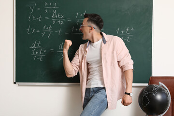 Happy Math teacher near chalkboard in classroom