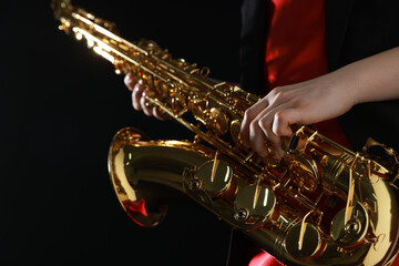 Professional musician with saxophone on black background, closeup