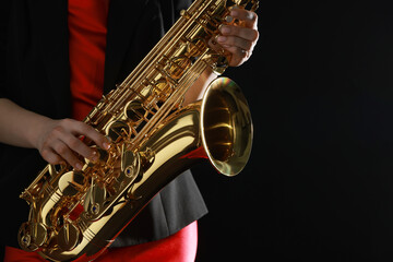 Obraz premium Professional musician with saxophone on black background, closeup